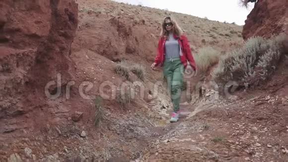 戴太阳镜的女游客在一个不寻常的地形上红色的山脉和红色的地球就像火星一样视频的预览图