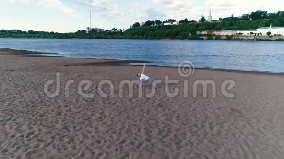 女人在城市河边的沙滩上做瑜伽美丽的景色视频的预览图