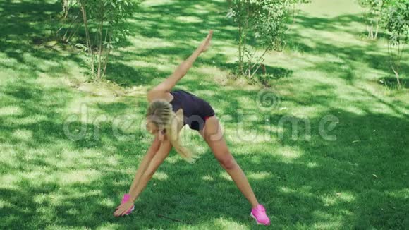 健身妇女训练伸展运动同时锻炼绿色公园视频的预览图