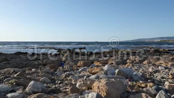 洛基海滩上堆满了塑料垃圾和垃圾船和山的背景慢动作视频的预览图