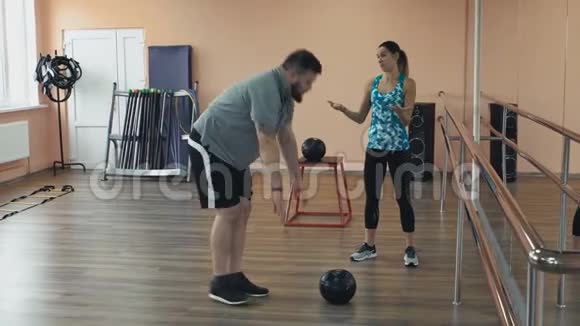 超重的男性和女性教练完美的身体燃烧卡路里通过锻炼体育女孩的个人训练视频的预览图