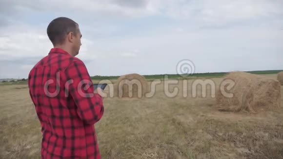 智慧农业理念一个农夫在一个数字平板电脑上研究生活方式中的干草堆慢动作视频的预览图