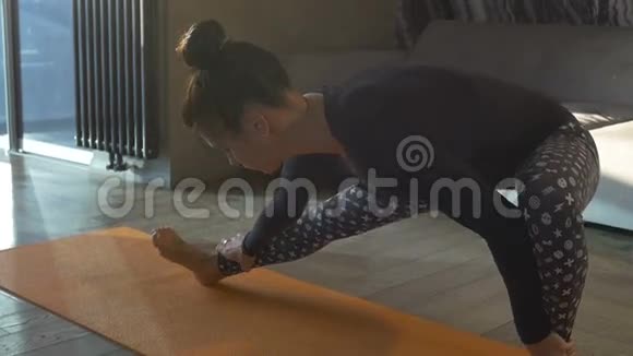 有魅力的女人在家里用垫子做健身运动视频的预览图