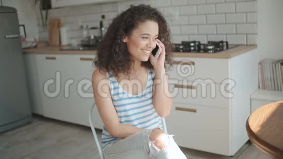 漂亮的年轻女人在明亮的厨房里打电话视频的预览图
