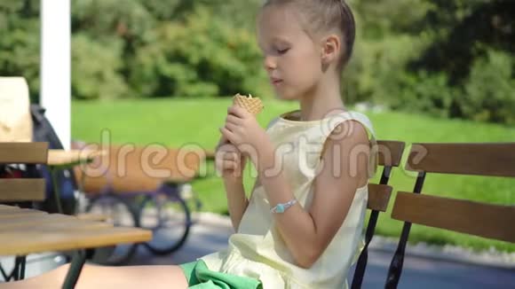 小女孩在户外吃冰淇淋夏天在户外咖啡馆视频的预览图