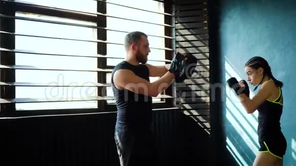 在健身房和拳击教练一起训练白人女拳击手视频的预览图