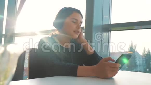快乐的年轻生活方式十几岁的女孩戴着耳机唱歌听着智能手机上的音乐社会中的少女视频的预览图