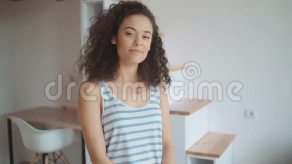 一位美丽的年轻女子在厨房里对着镜头微笑的肖像视频的预览图