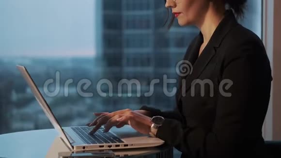 办公室里戴眼镜的女商人的肖像坐在桌子旁用笔记本电脑工作的女孩视频的预览图