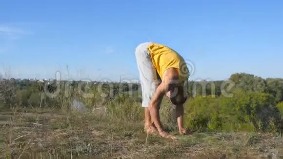 在户外练习瑜伽动作和姿势的人年轻男子站在瑜伽姿势的自然做体力活的运动员视频的预览图