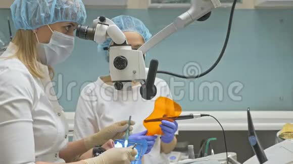 医生用过显微镜牙医在现代牙科诊所治疗病人正畸医生与助理一起工作行动视频的预览图