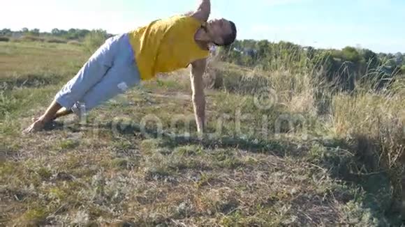 在户外练习瑜伽动作和姿势的人年轻男子站在瑜伽姿势的自然做体力活的运动员视频的预览图