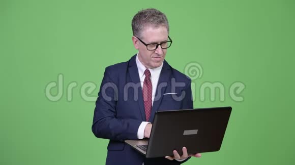 一张成熟的商人在使用笔记本电脑时思考的摄影棚视频的预览图