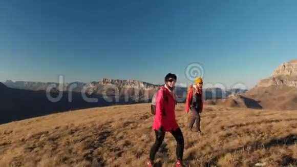 两个女孩的旅行者带着背包和照相机漫步在山上史诗般的岩石之间视频的预览图