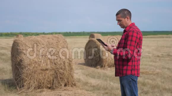 智慧农业概念生活方式一个工人农民在数字平板电脑上的田野里研究干草堆慢慢视频的预览图