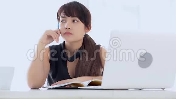 美丽的亚洲女人微笑着坐在客厅里学习在家写笔记本女孩做作业视频的预览图