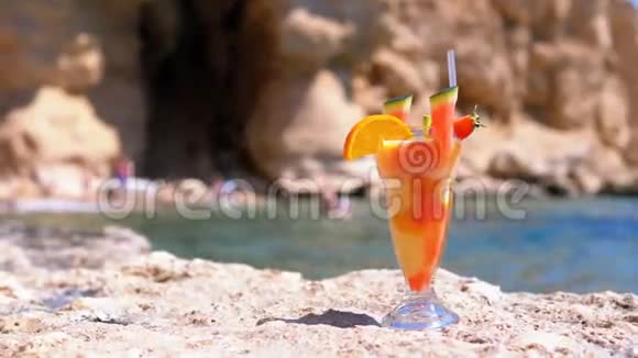 埃及海滩上的麦秆玻璃中的热带鲜榨果汁矗立在海边的岩石上视频的预览图