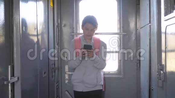 带着生活方式背包的少女旅行者站在火车车窗旁手里拿着智能手机旅费视频的预览图