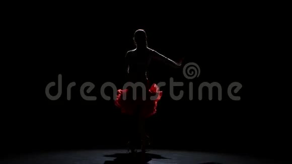 女人在黑暗背景下的工作室里跳拉丁舞剪影视频的预览图