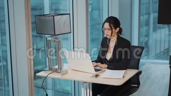 女商人在一间现代化办公室的餐桌上工作的肖像女商人坐在电脑旁视频的预览图