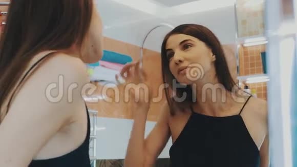 年轻的黑发女孩在浴室里照镜子仔细检查眉毛面子视频的预览图