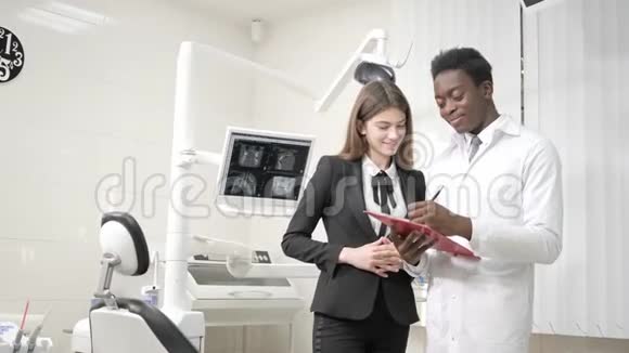 年轻的非裔美国男医生牙医和美丽的女孩病人在牙科诊所医学卫生口腔科视频的预览图