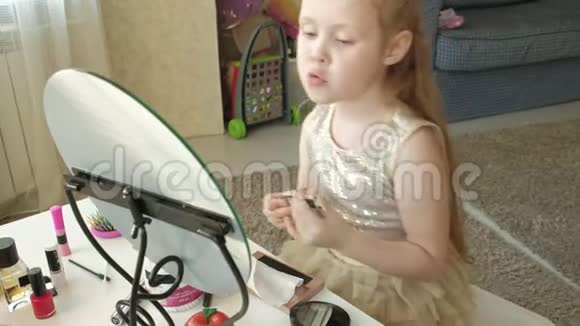 一个红头发的小女孩戴上遮瑕膏照镜子化妆脸时尚风格化妆品视频的预览图
