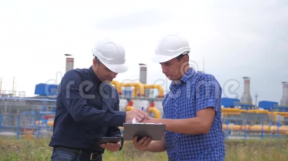 团队合作工业生活方式煤气生产站的概念慢动作视频两名戴头盔的工程师正在学习视频的预览图