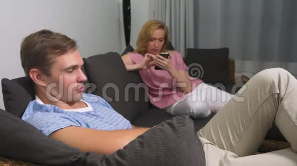 两次危机男人和女人在客厅沙发上过夜女人用电话男人是视频的预览图