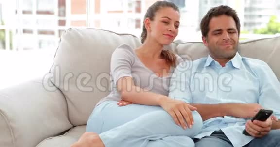 放松的夫妇在沙发上看电视视频的预览图