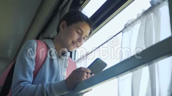 少女生活方式旅行者带着背包站在火车的窗户边带着智能手机旅费视频的预览图