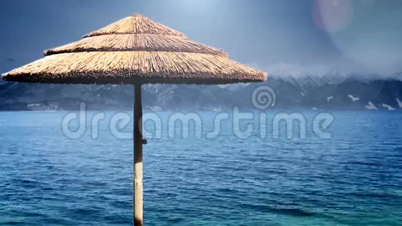 蓝水海滨的沙滩伞雪峰背景视频的预览图