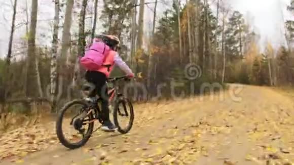 一个高加索儿童在秋季公园骑自行车小女孩骑着黑色橙色的自行车在森林里孩子是干的视频的预览图