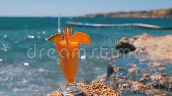 热带鲜鸡尾酒埃及海滩上的麦秆玻璃矗立在红海背景的岩石上视频的预览图