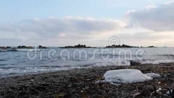 沙滩上的塑料袋海浪拍打海岸海滩污染慢动作视频的预览图