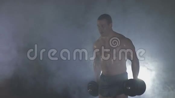 强壮的运动员在烟雾中举起沉重的哑铃视频的预览图