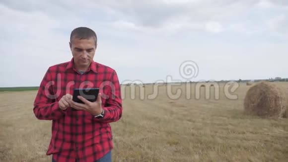 智慧农业理念农夫在数字平板电脑上的田野里研究干草堆慢生活方式慢生活方式视频的预览图