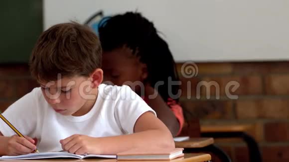 小男孩在教室里写记事本视频的预览图
