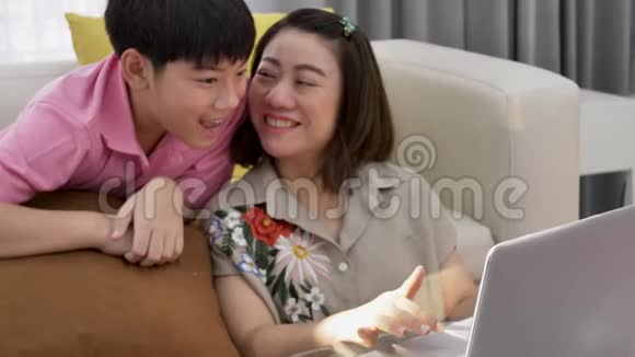 亚洲母子在笔记本电脑上微笑着看着视频的预览图