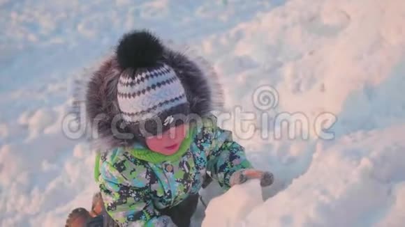 一个小孩子正在冬天的公园里玩雪晴朗的冬日新鲜空气中的乐趣和游戏视频的预览图