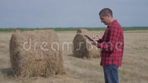 智慧农业理念男子工人农民研究干草堆在田间生活方式的数字平板电脑慢慢视频的预览图