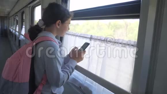 带背包的少女旅行者站在装有智能手机的火车车厢的橱窗里旅费视频的预览图
