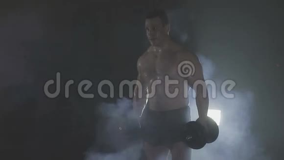 强壮的运动员在烟雾中举起沉重的哑铃视频的预览图