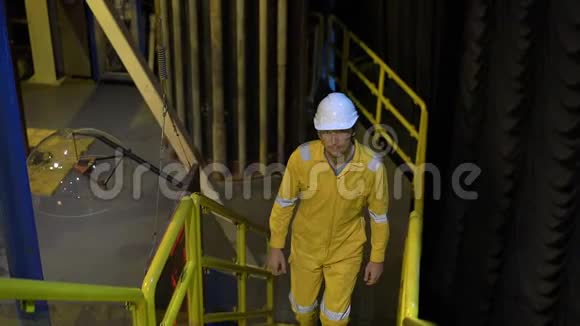 在工业环境石油平台或液化气体工厂穿黄色工作服戴眼镜和戴头盔的年轻人视频的预览图