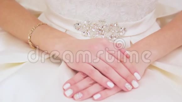 新娘的手在白色礼服上做指甲视频的预览图