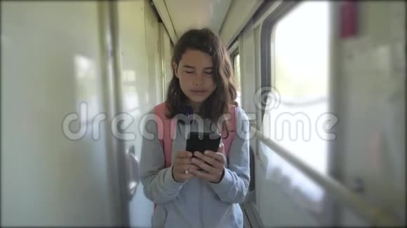 十几岁的女孩带着背包和智能手机在火车车厢里散步旅游运输铁路概念a视频的预览图