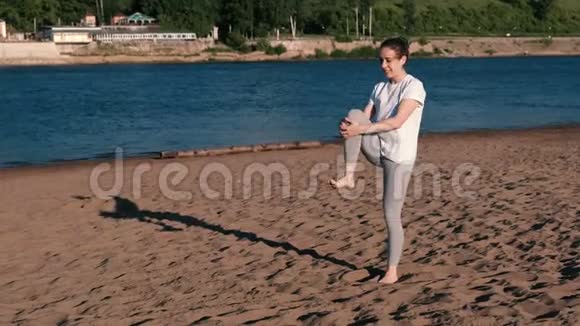 女人在城市河边的海滩上伸展瑜伽美丽的景色视频的预览图
