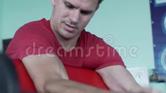 肌肉男训练肱二头肌与Barbell在健身房视频的预览图