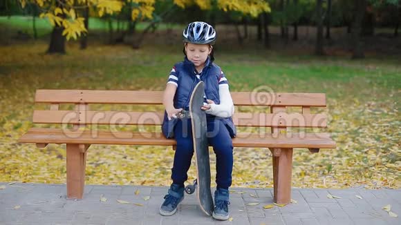 一个手臂骨折的白人男孩坐在溜冰场视频的预览图