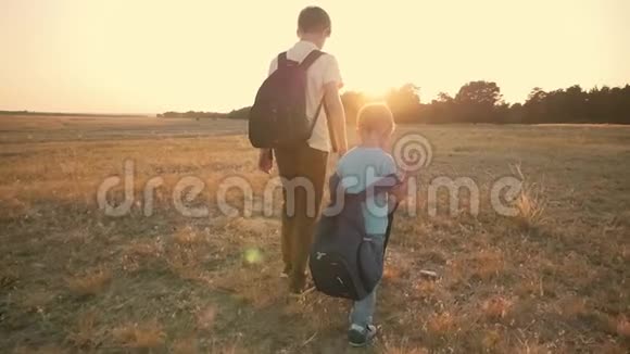 两个旅行者日落时分两个男孩带着背包沿着田野走着家庭和旅行的概念视频的预览图